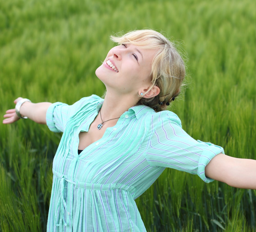 Photo of adult woman in a grass field with a happy expression in their face
