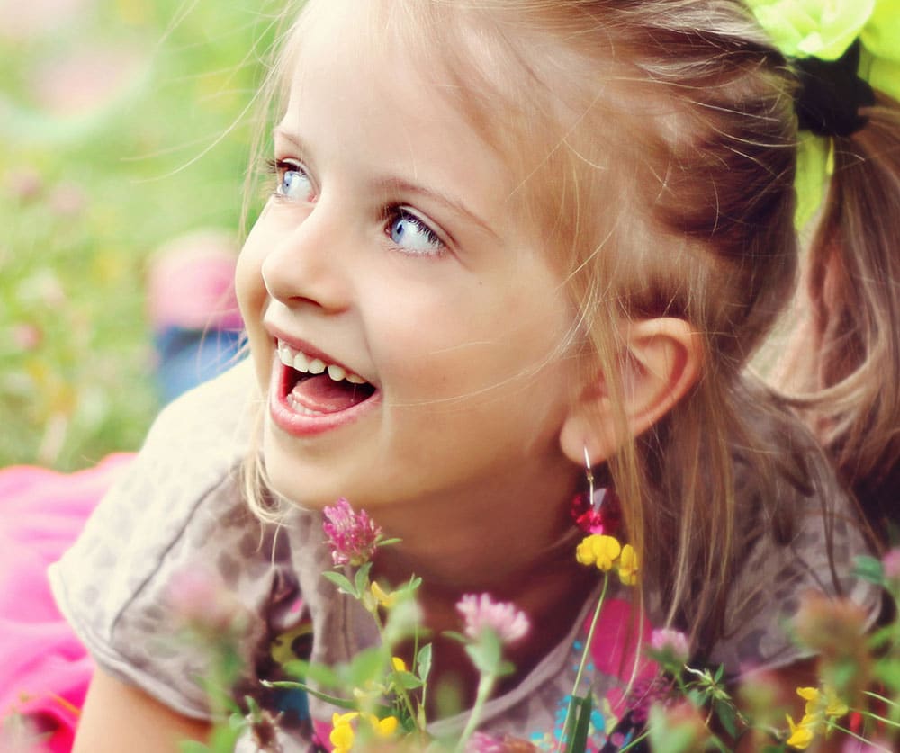 Closed up photo of a young girl in a garden with a happy expression on their face